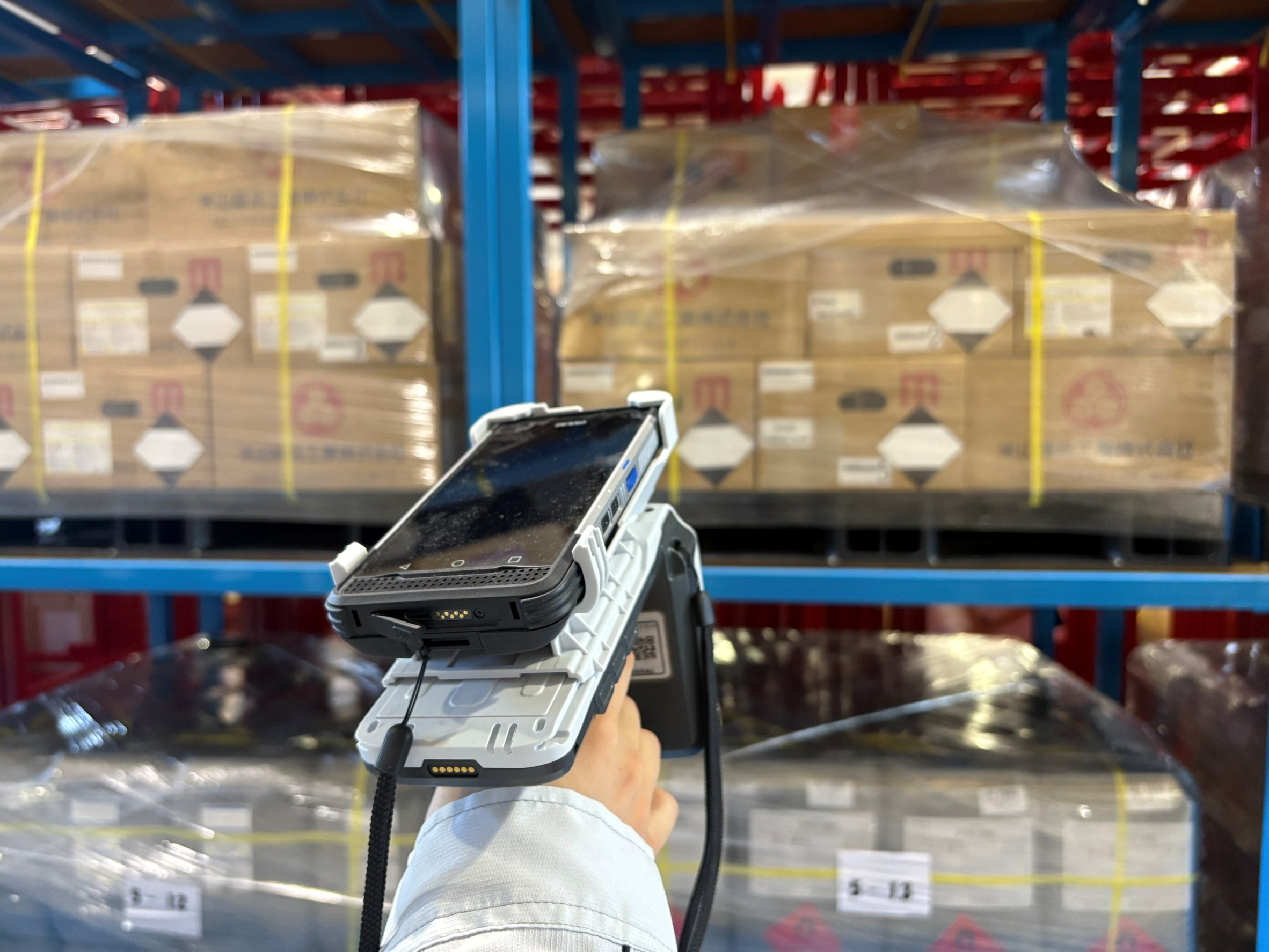 倉庫内の在庫管理で、ハンディ端末を使用して商品情報を確認している様子（RFID）